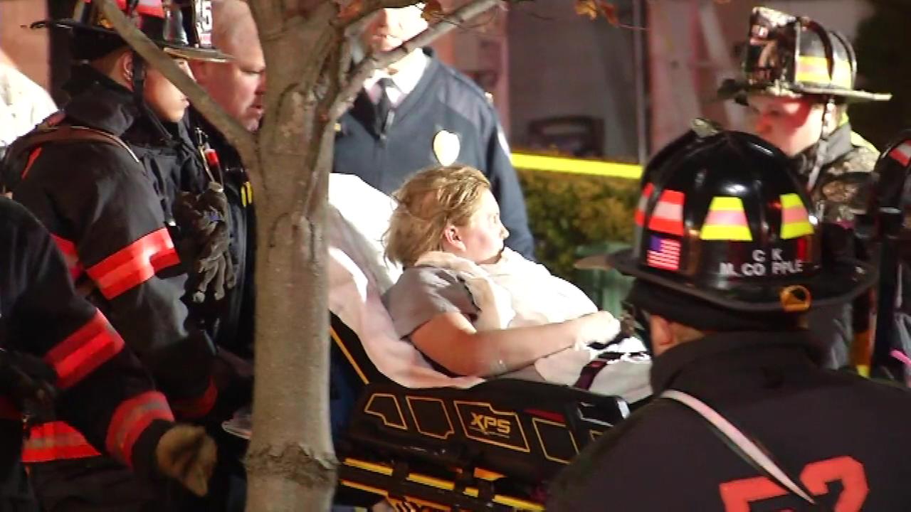 Woman on stretcher being helped by firefighters.