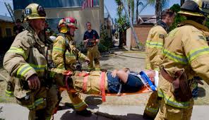 A Group Of Firefighters Standing Around An Injured Person.